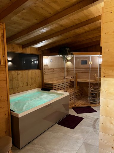 Wellnessbereich mit Whirlpool und Sauna in Holzverkleidung.