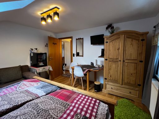 Ein gemütliches Zimmer mit zwei Betten, Schreibtisch, Holzschrank und Fernseher.