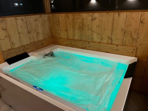 Whirlpool mit blauen Lichtern in einem Holzverkleideten Raum.
