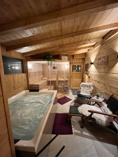 Wellnessbereich mit Holzverkleidung, Whirlpool, Liegen und sanfter Beleuchtung.