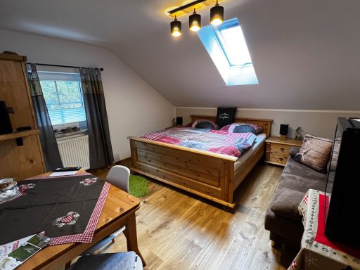 Heller Schlafraum mit Doppelbett, Tisch, Stuhl und gemütlicher Couch.